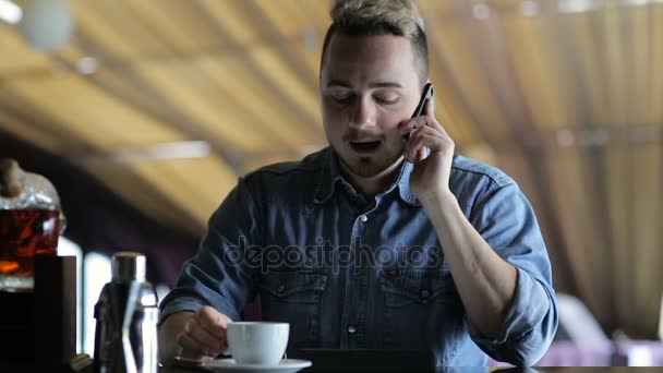 En ung man pratar i telefon när du sitter i baren — Stockvideo