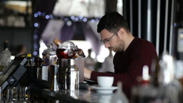 A young man uses tablet while sitting at the bar — Stock Video