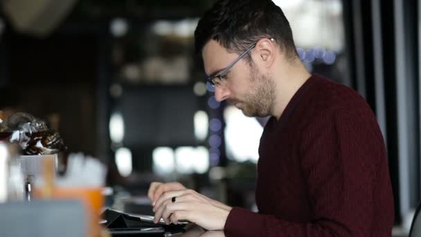 Mladý muž psaním na tabletu při posezení v baru — Stock video