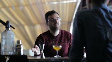 Genç barmen müşteriyle iletişim kurar ve ona bir kokteyl hazırlar.