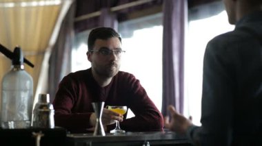 Genç barmen müşteriyle iletişim kurar ve ona bir kokteyl hazırlar.