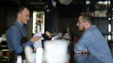 Barmen, barda genç bir adamla konuşuyor.