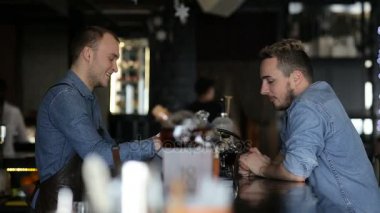 Barmen, barda genç bir adamla konuşuyor.