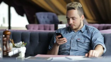 Restoranda oturan adam, cep telefonuyla mesaj atıp gülümsüyor