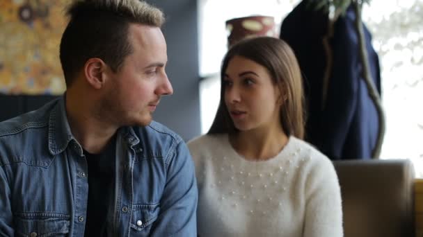 Twee jonge, lachende en tevreden mensen hebben een gesprek in het café — Stockvideo