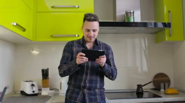 Tablet ayakta mutfakta evde oynarken oyun genç adam