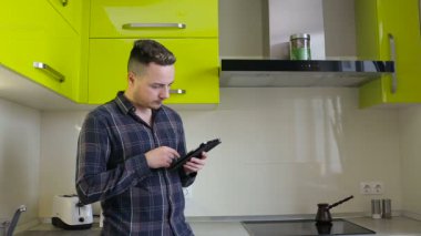 Haber tablet bilgisayarda okuma ve mutfakta kahve içme adam