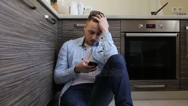 Smutný mladík pomocí smartphone v kuchyni — Stock video
