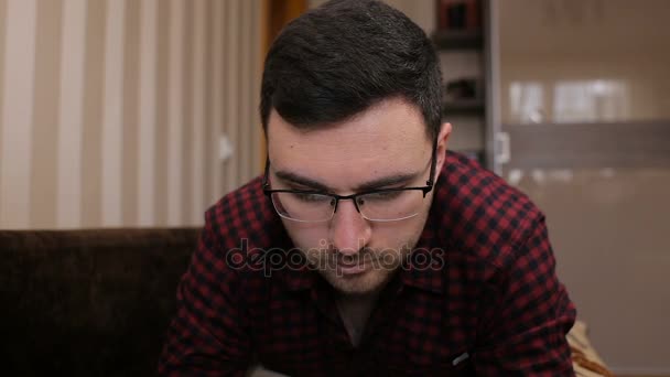 Young man lying on the couch and gaining a sms on a tablet — Stock Video