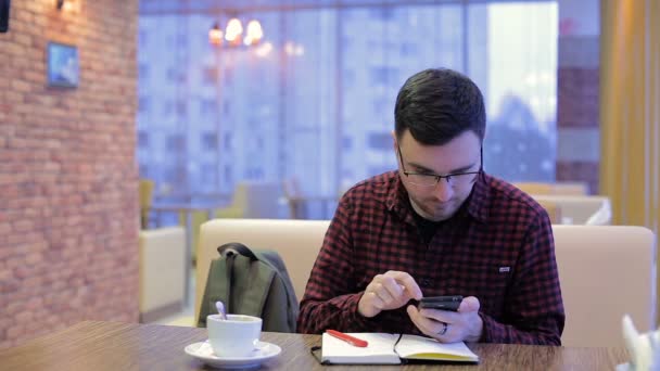 Hombre adulto hablando por teléfono y escribiendo en un cuaderno en la cafetería — Vídeos de Stock