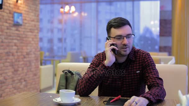 Молодий чоловік розмовляє по мобільному телефону в кафе — стокове відео