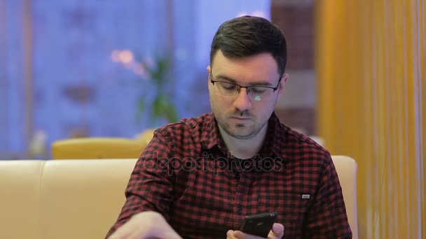Volwassen man op telefoon praten en schrijven in een notitieblok in café — Stockvideo