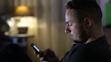 adam evde kanepede oturan smartphone ile