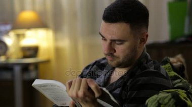 Adam geceleri evde kanepede oturup kitap okuma