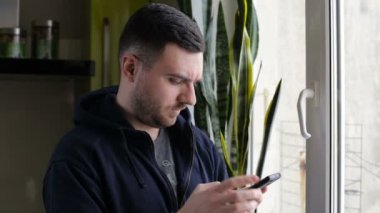 Akıllı pencere kenarındaki evde genç, mutlu bir adam manifatura