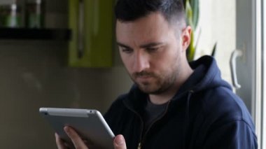 Pencere kenarındaki evde tablet ile ayakta adam