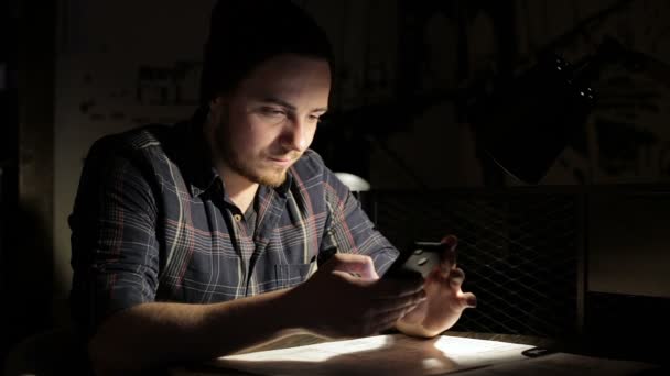 Jeune homme utilisant un smartphone dans un café dans la nuit — Video