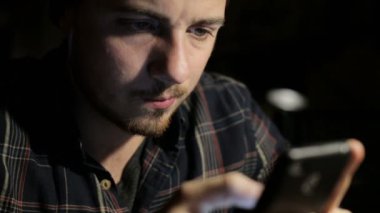 Genç adam bir restoran yakın çekim gece smartphone kullanır