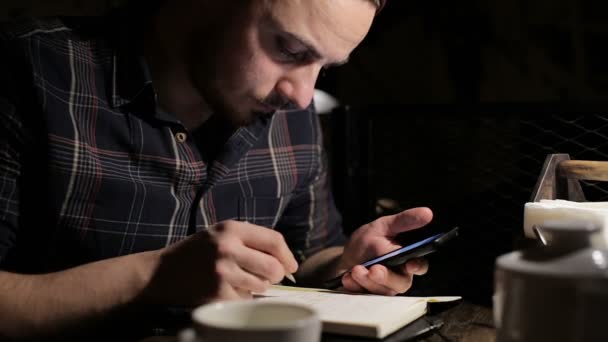 Jeune homme écrivant une liste de choses à faire dans un bar la nuit — Video