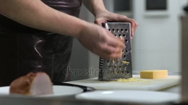 Man hand grating yellow cheese with a metal grater — Stock Video