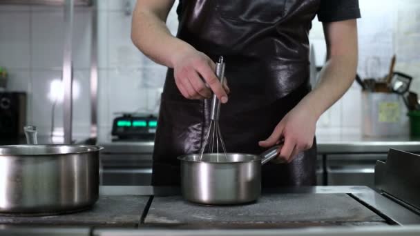 De chef-kok is koken de saus op het fornuis — Stockvideo