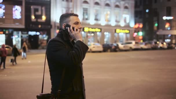 Młody człowiek rozmawia przez telefon odkryty w nocy w mieście — Wideo stockowe