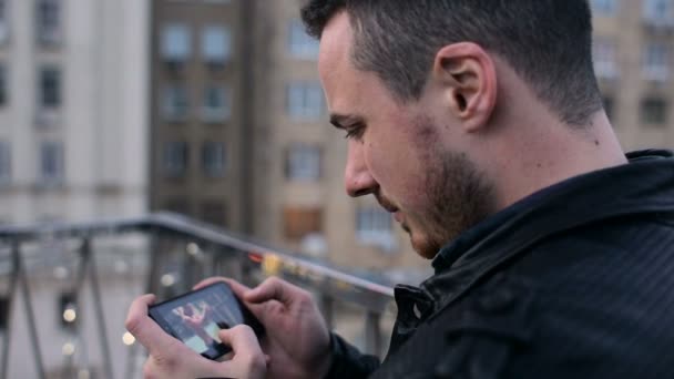 Молодой красивый мужчина с бородой и мобильным телефоном на крыше в городе — стоковое видео