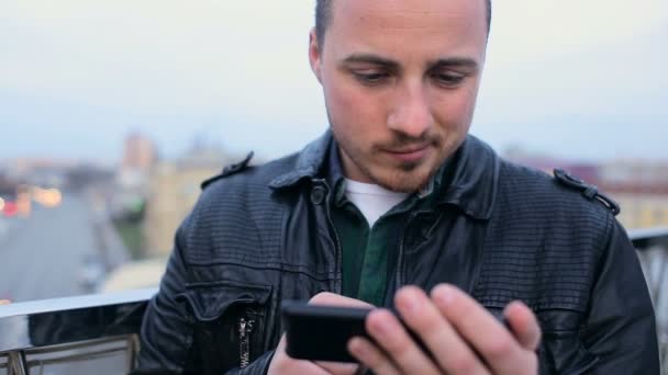 Jovem homem bonito com barba com telefone celular no telhado na cidade — Vídeo de Stock