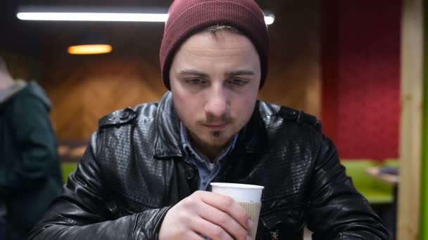 Ο άνθρωπος χρησιμοποιώντας κινητό και πίνοντας τον καφέ στην καφετέρια — Αρχείο Βίντεο