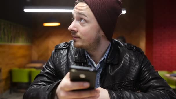 Człowiek za pomocą telefonów komórkowych i picia kawy w kawiarni — Wideo stockowe