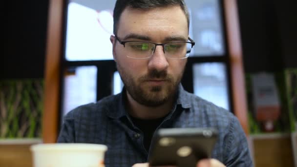 Чоловік використовує мобільний телефон і п'є каву в кафе — стокове відео