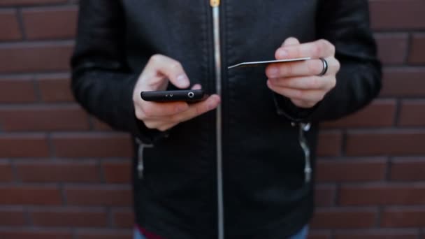 Mladý muž, nákupy s kreditní kartou v jedné ruce a smartphone na straně druhé — Stock video