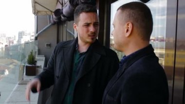 Bir restoranda balkonda konuşan iki genç iş adamları