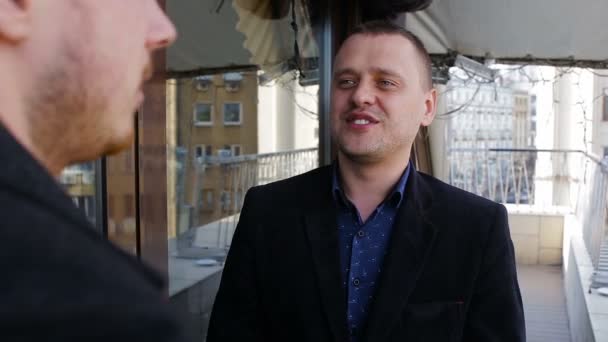 Два молодых бизнесмена разговаривают на балконе в ресторане — стоковое видео