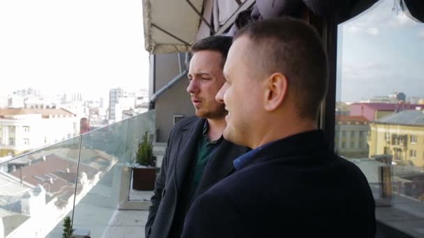 zwei junge Geschäftsleute unterhalten sich auf dem Balkon eines Restaurants