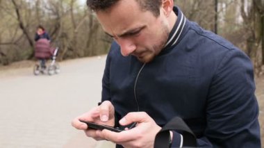 Dokunmatik ekran telefon parkta oynayan genç adam