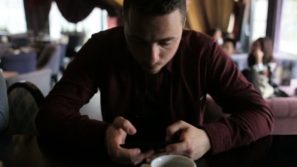Hombre jugando juego en el teléfono inteligente sentado en el bar — Vídeos de Stock