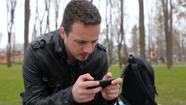 Hombre jugando en el teléfono en el parque — Vídeos de Stock