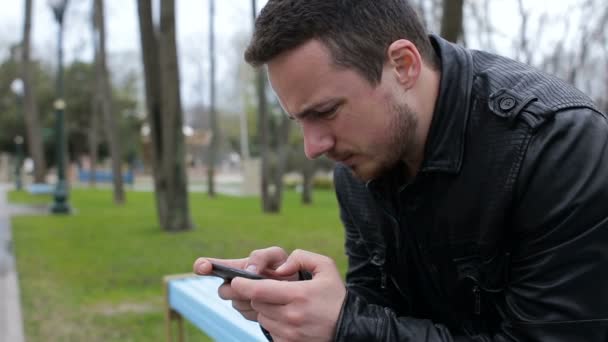 Sám muž hraje na telefonu v parku — Stock video