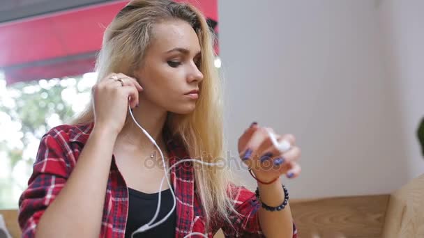 Smutna dziewczyna, słuchanie muzyki na telefon w kawiarni — Wideo stockowe