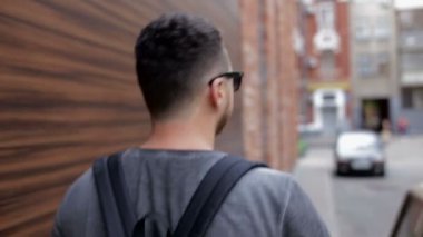 Adam tuğla duvarın yanında şehir etrafında yürüyor