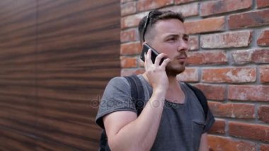 Tuğla duvarın yanında telefonda konuşan adam