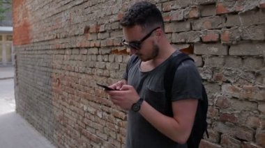 Adam bir tuğla duvar yakınındaki bir akıllı telefon kullanır