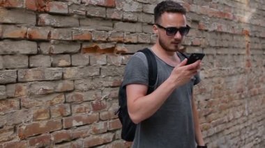 Adam bir tuğla duvar yakınındaki bir akıllı telefon kullanır. Slo hareket ateş