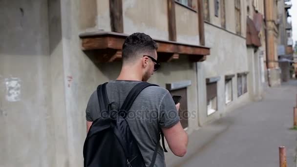 Um turista na cidade velha faz uma foto da casa e caminha — Vídeo de Stock