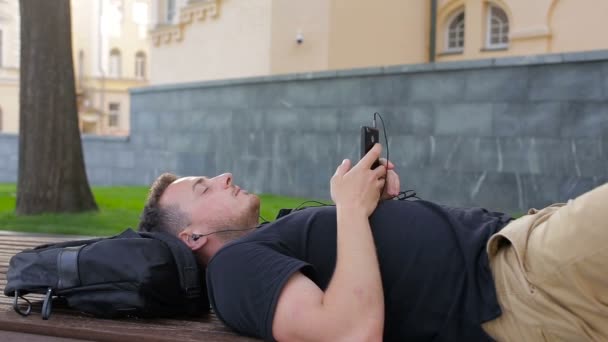 Gelukkig man luisteren naar de muziek op smartphone in de stad — Stockvideo