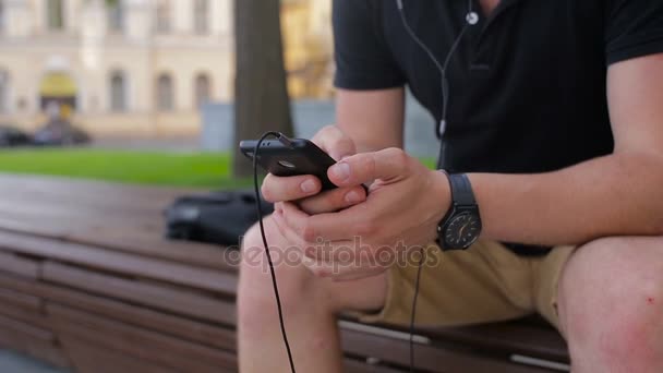 Joven hablando por teléfono móvil en un banco de la ciudad — Vídeos de Stock