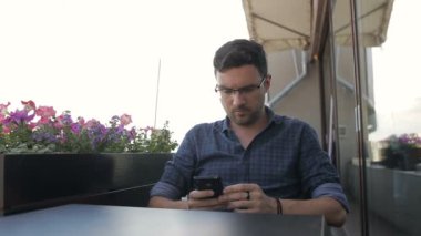 Telefon ile kafede oturan genç yakışıklı adam