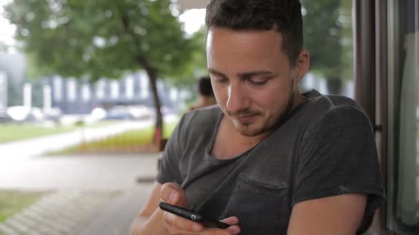 Νεαρός άνδρας μιλάει στο τηλέφωνο σε ένα καφενείο στο δρόμο — Αρχείο Βίντεο