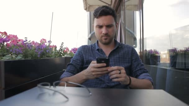 Jonge knappe man zitten in cafe met telefoon — Stockvideo